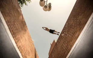 شاب بمهارة خارقة لا يعترف بالجاذبية الأرضية ويتسلق جدران وشرفات المنازل! (فيديو)