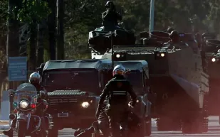 لصوص يسطون على بنك ويتخذون الرهائن دروعا بشرية أعلى السيارات ! (فيديو)