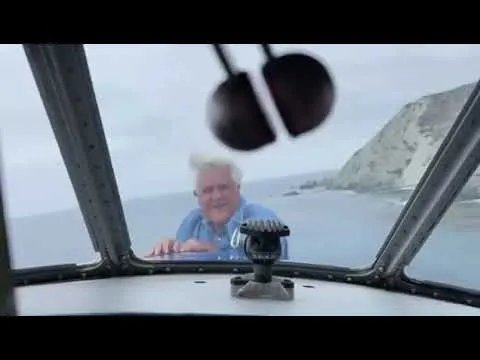 مذيع يتعلق بمقدمة طائرة أثناء تحليقها فوق البحر (فيديو)