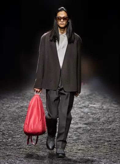 حقيبة عصرية ومميزة باللون الأحمر من Zegna تنسجم مع سترة مبتكرة وسروال أنيق، وتزداد الإطلالة جمالًا مع قميص وكنزة باللون الأبيض - المصدر: Zegna موضة الأحمر… أحادية متوهجة وجريئة