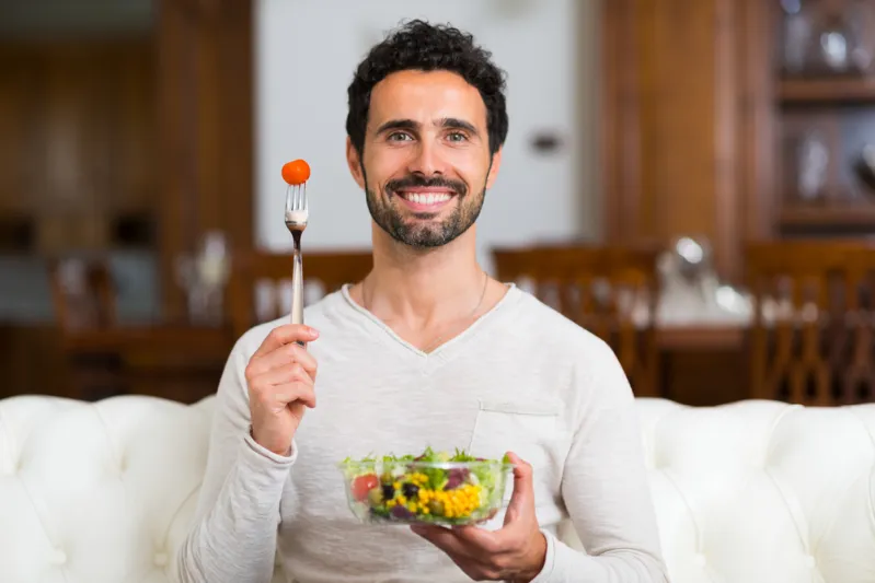 رجل مبتسم يحمل طبق طعام نباتي تعبيرية عن نظام "أومني" الغذائي - المصدر: Shutterstock نظام أومني الغذائي.. هل هو مثالي لخسارة الوزن وكيف تلتزم به؟