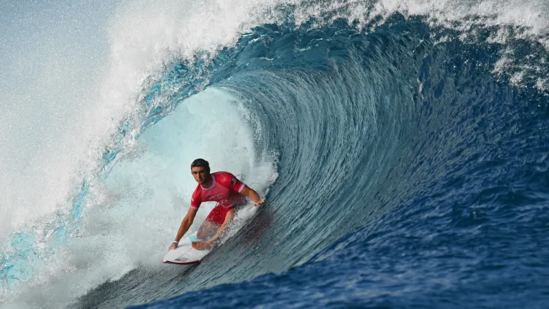 مشهد نادر يوثق تناغم راكب أمواج مع عشرات الدلافين البرية (فيديو)