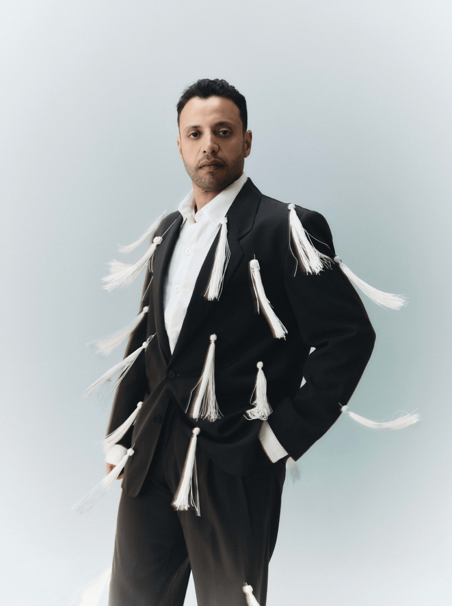 HAJ RUSS بدلة سوداء بتفاصيل متحرّكة تكسر الصرامة الكلاسيكية، وتعكس روحاً جريئة تمزج بين الحضور الرسمي والطابع الفني المعاصر