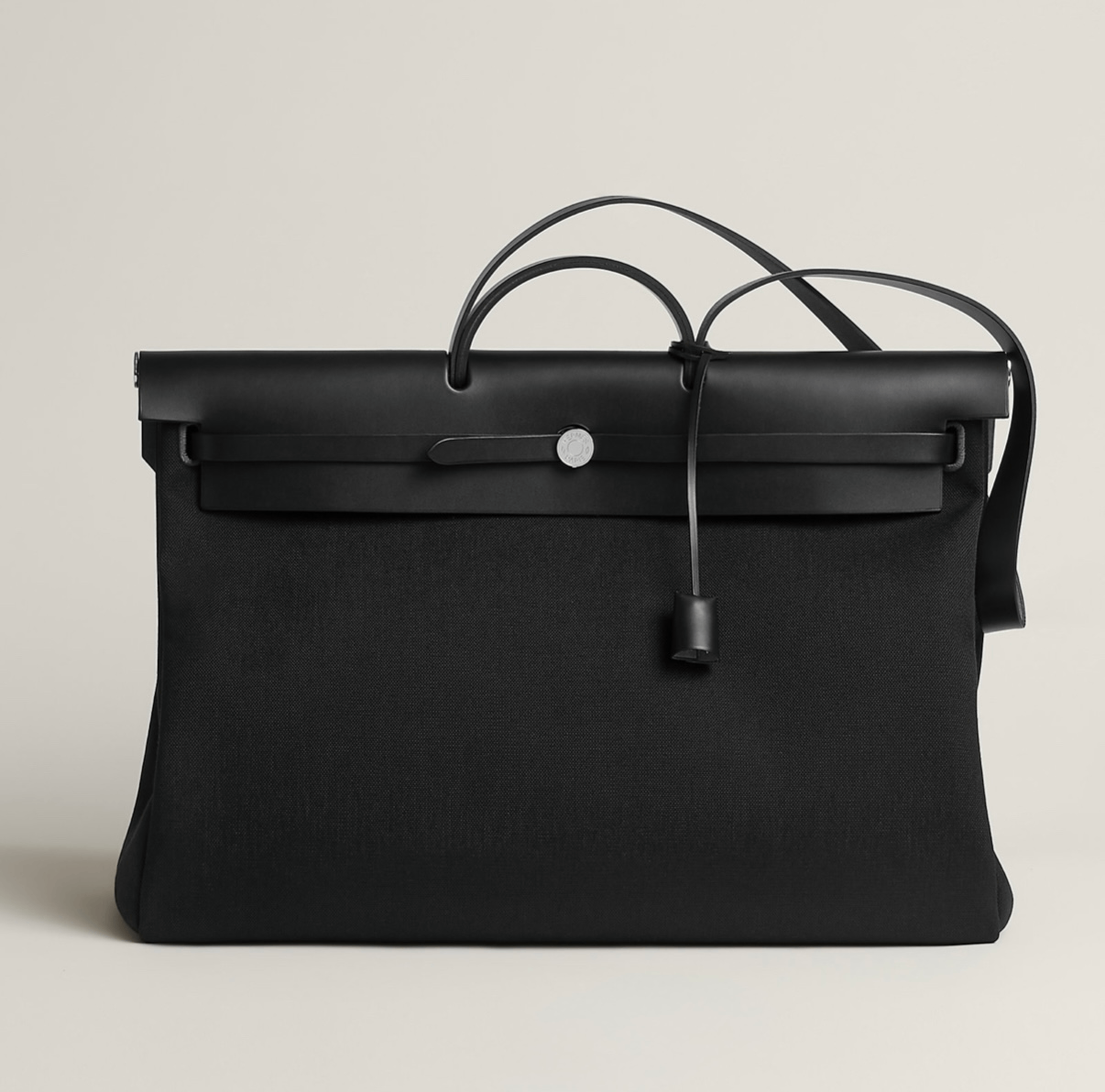 حقيبة Hermès Herbag Zip بتصميم أسود أنيق يجمع بين القماش المتين والجلد الناعم، تعكس روح الدار العملية مع لمسة فخامة هادئة تناسب الاستخدام اليومي والسفر.