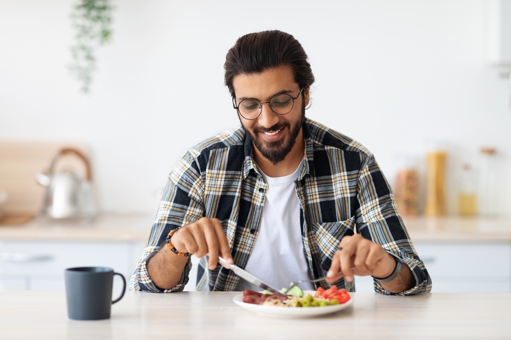 رجل يتناول طعامه سعيدًا تعبيرية عن خطط غذائية مخصصة أحد مزايا رجيم النمط الأيضي