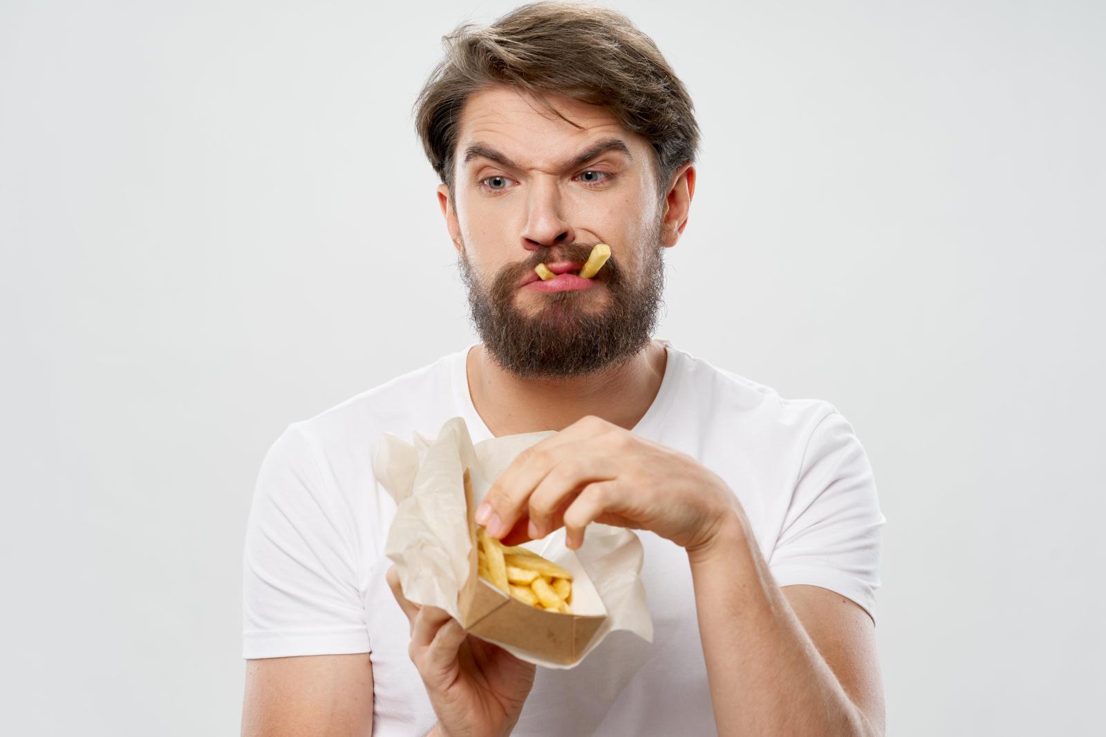 رجل متوتر يتناول بطاطس مقلية تعبيرية عن التوتر من أسباب اشتهاء الأطعمة الحارة فجأة