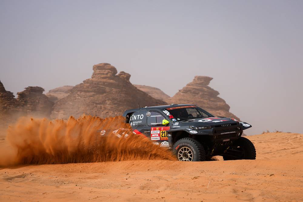 سيارة سباق تخترق الكثبان الرملية بين التكوينات الصخرية في المرحلة الثالثة من رالي داكار 