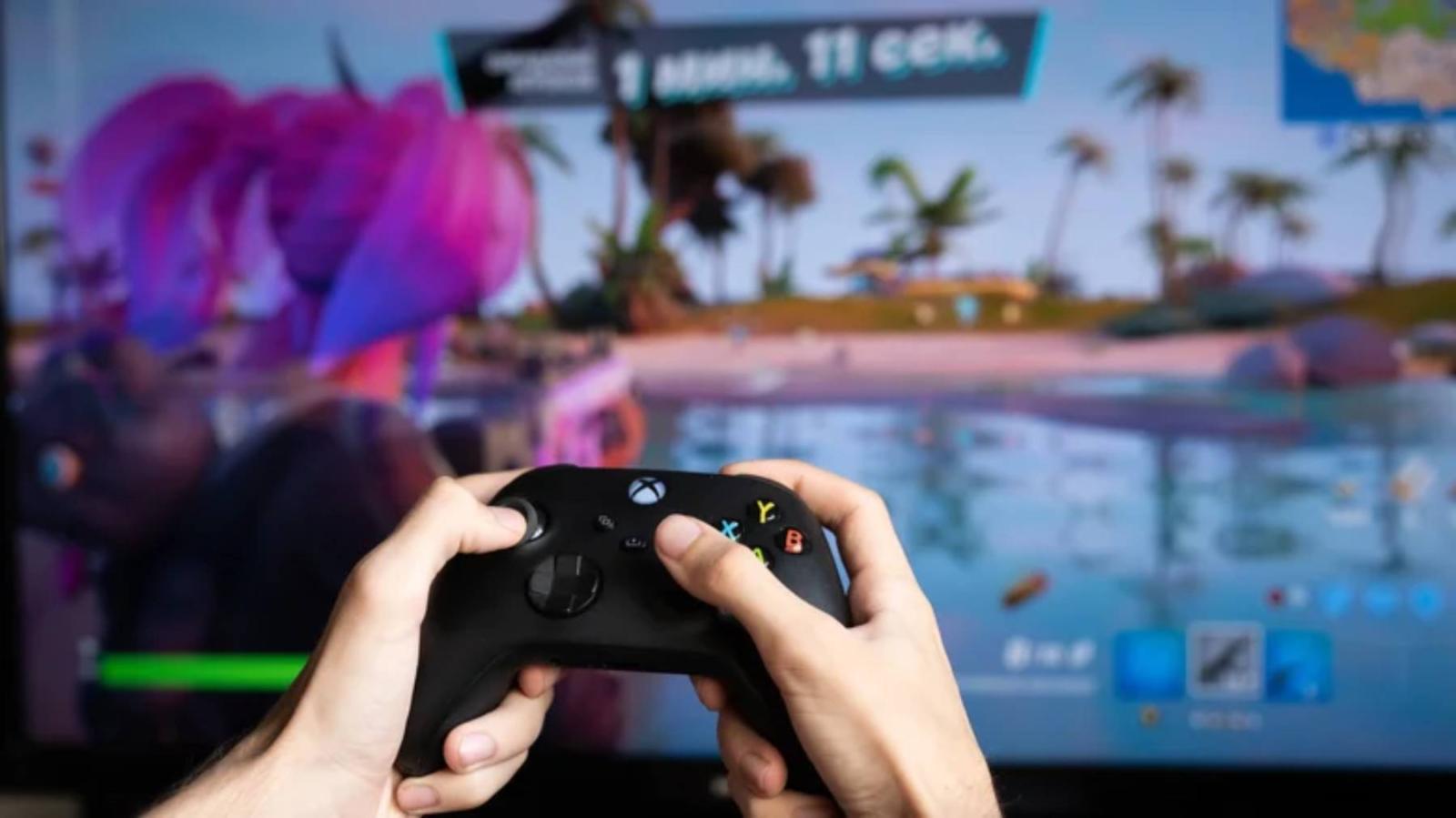 لاعب يستخدم يد تحكم Xbox أثناء تشغيل لعبة على الشاشة 
